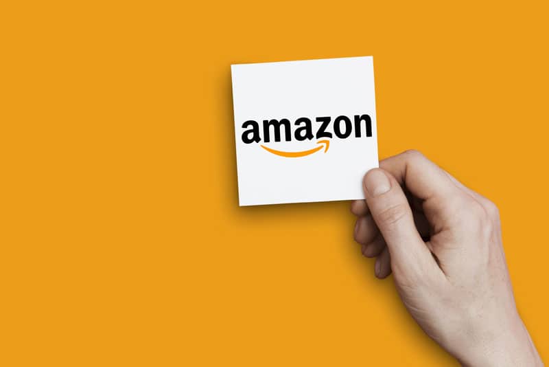 Photo of a person holding a white card with the amazon logo on it